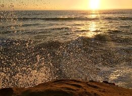 Splash of wave on rock in front of sea at Sunset