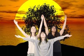 three girls with hands up at sunset