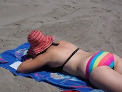 girl lies on a bedspread on the beach