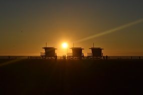lifeguard towers on the beach against a golden sunset