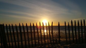 fence along the ocean at sunset