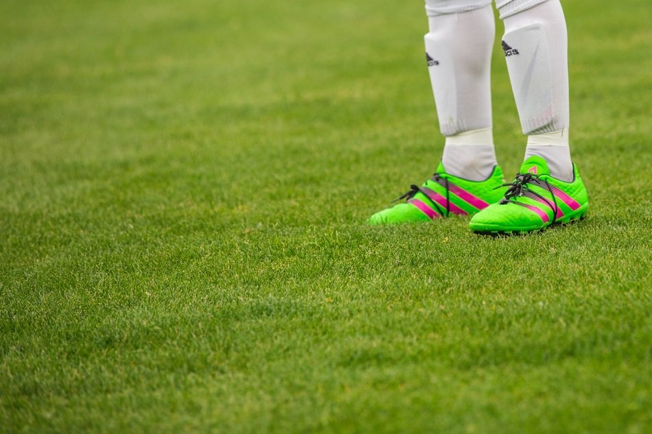 Footballer’s legs in shin savers and soccer shoes on Field