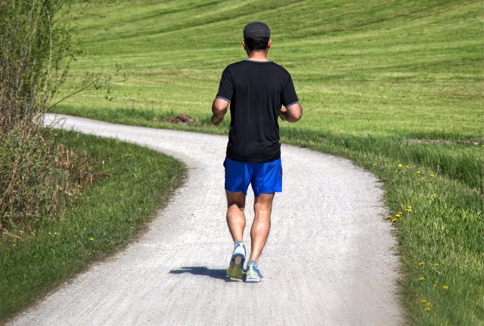 Jogger, man Running away on winding road at field