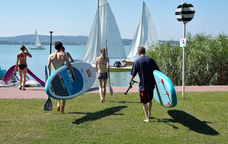 men with boards and oars walk along the shore of Lake Balaton