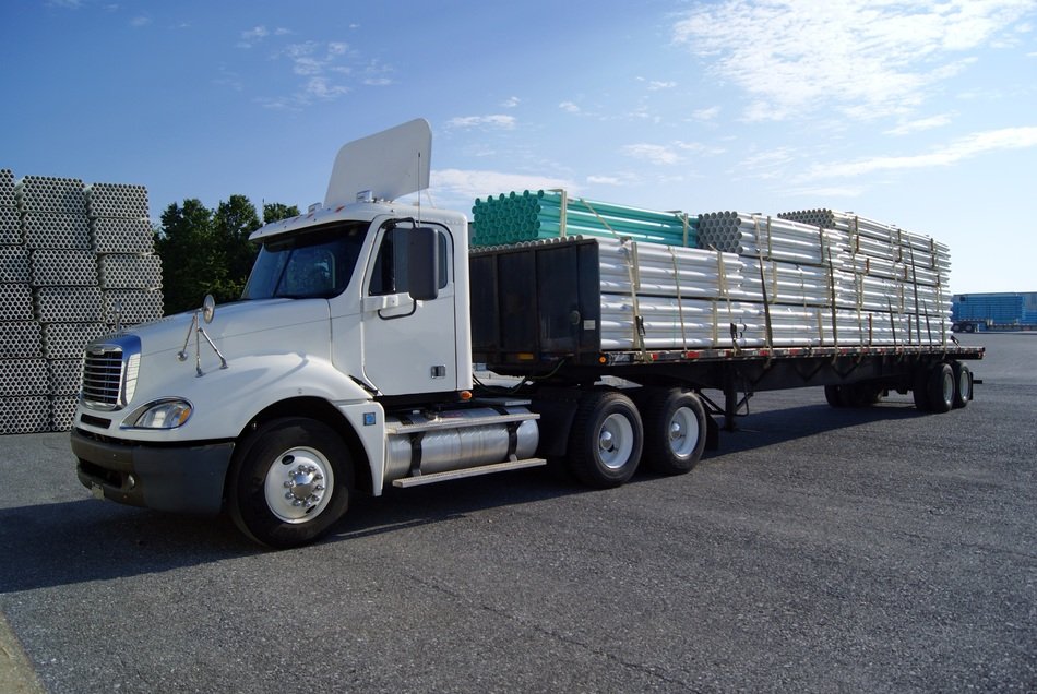 white flatbed Truck Loaded with pipes