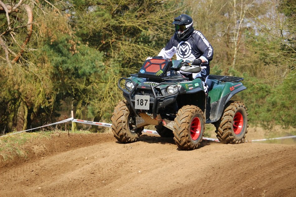 athlete on cross-country ATV among green plants