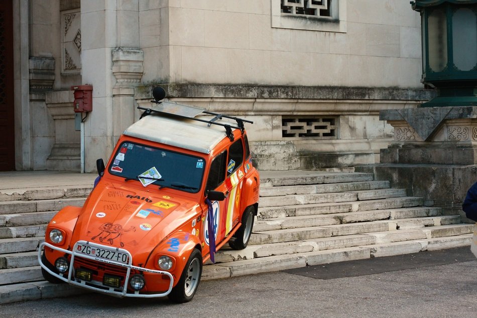 orange retro car on the stone steps of the building