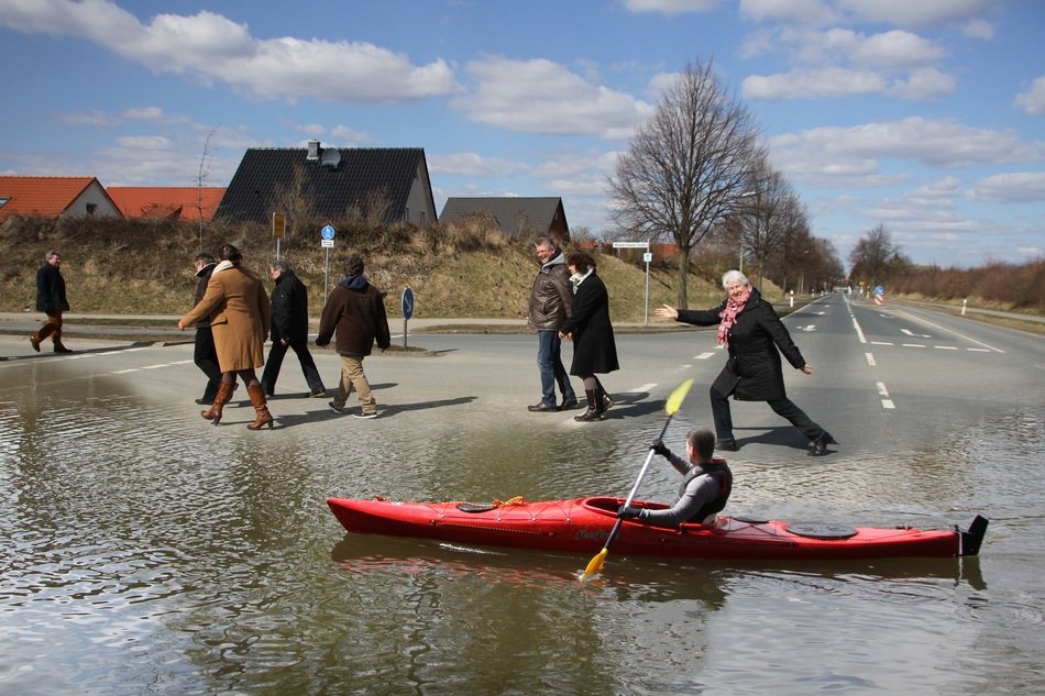 High Water in village, man Canoeing across Road