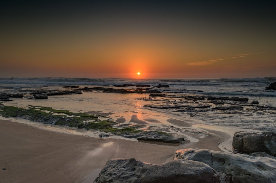 view from the beach to the sunrise on the ocean horizon