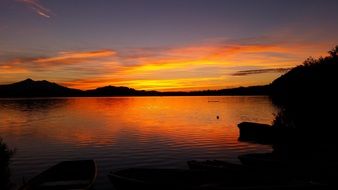 golden evening sky reflected in the lake with silhouettes on the shore