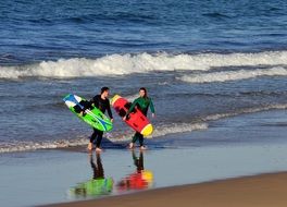 surfers with boards by the ocean