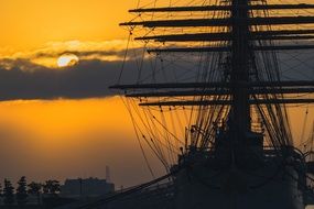Silhouette of the sailing ship at colorful sunset background