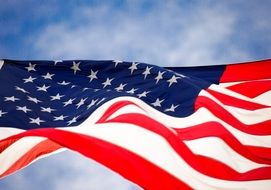 american flag on blue sky background with clouds