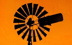 Black silhouette of the windmill on the orange background