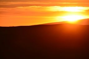 sunset on the horizon over sand dunes