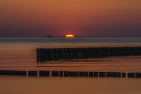silhouettes of groynes at sunset