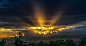 the rays of the evening sun behind dark clouds