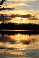golden clouds at sunset sky mirroring on water
