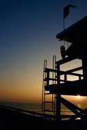 silhouette of a lifeguard on the beach during sunset, california