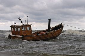 old wooden Boot anchored on stormy sea