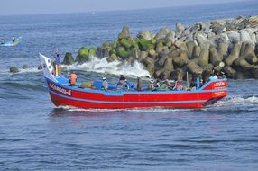 Fishing red Boat in the waves in the trivandrum