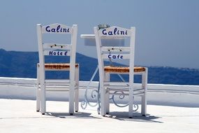 white chairs against the backdrop of a picturesque Greek landscape