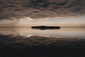 island in the ocean under dark clouds