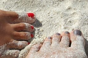 bare feet with a pedicure in the sand close-up