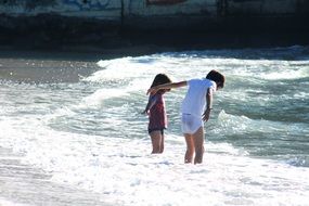 children on the beach in the waves of the surf
