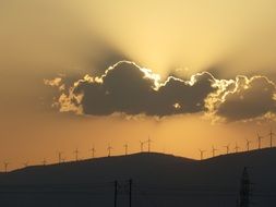 row of Wind Turbines on hill at Sunset Sky