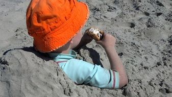 child in an orange hat in the sand