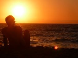 silhouette of a man on the beach at orange sunset