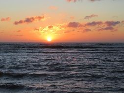 setting sun in the clouds on the horizon above the water