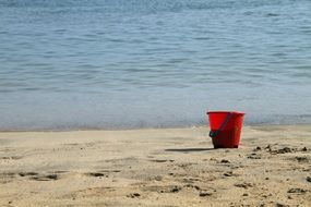 red plastic bucket on the beach