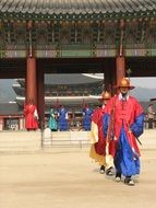 Asian men in national costumes on the background of the Genbokgun palace complex in Seoul