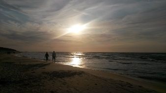 couple walking on beach at sunset