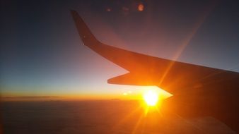 the golden sun behind the wing of an airplane