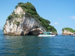 boat is floating near the rock in ocean