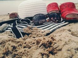 hat red glasses and sandals on the sand