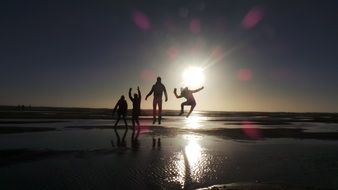 silhouettes of people in the bright sun on the beach