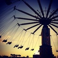 silhouettes of people on Yo-Yo Swing at sunset sky