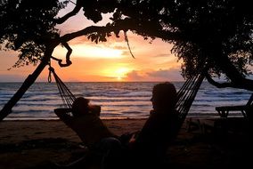 Relaxing man on a hammock at the sunset