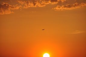 bright orange sky with a half sun and clouds