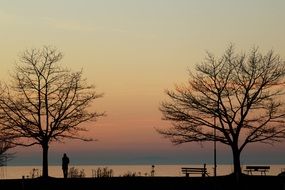 distant view of a lonely man on the shores of Lake Constance at sunset