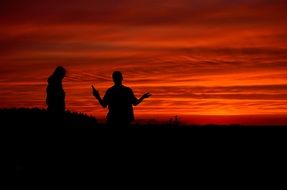 silhouettes of people against a red sunset