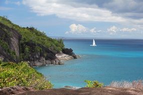 distant view from the shore to a sailboat in the waters of the Caribbean