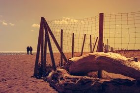 couple walking on the beach with a fence