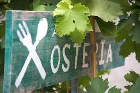 restaurant sign among green leaves in italy