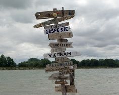 wooden pole with directions of cities on the beach