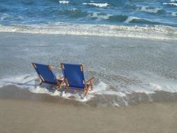 two blue deck chairs on the surf